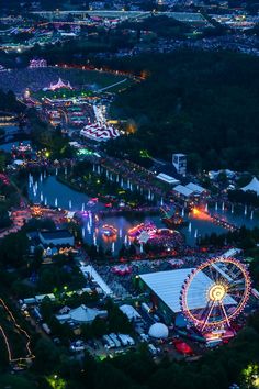 an aerial view of a fairground at night with ferris wheel and lights in the background