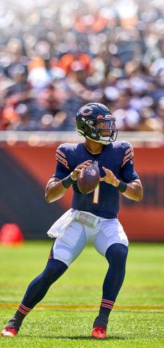 a football player holding a ball on top of a field in front of an audience