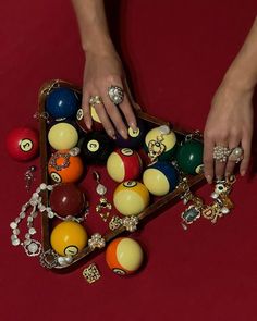 a woman's hand reaching for some balls on a red surface with other items