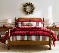 a bedroom decorated for christmas with plaid bedding and wreaths on the wall above