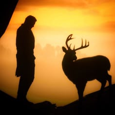 the silhouette of a man standing next to a deer