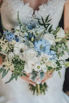 a bride holding a bouquet of white and blue flowers