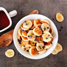 a white bowl filled with bananas and chocolate chips next to a cup of hot tea