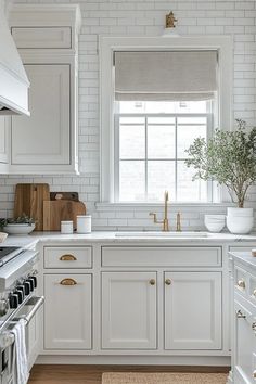 a kitchen with white cabinets and gold hardware on the handles, windows, and drawers