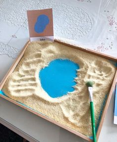 a blue pool in the sand with a green toothbrush next to it on a table