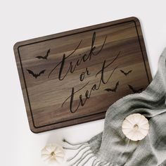 a wooden sign that says trick or treat next to some pumpkins and a scarf