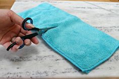 someone is cutting fabric with scissors on a counter top in front of a blue towel