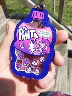 a hand holding a purple and pink keychain with an image of a cartoon character on it