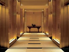 an empty hallway in a building with gold walls and floor tiles on either side of the room