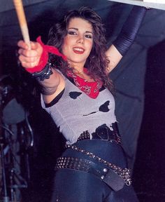 a woman holding a baseball bat in her right hand and wearing tight black leather pants