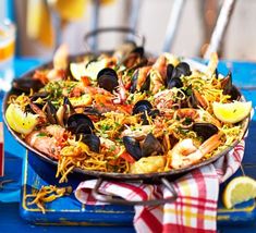 a pan filled with seafood and mussels on top of a blue table