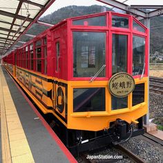 a red and yellow train pulling into a station