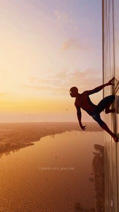 a man climbing up the side of a tall building in front of a body of water