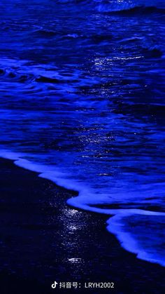 the moon is shining over the water at night on the beach with dark blue waves