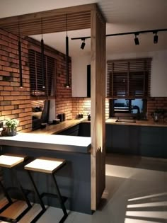 a kitchen with an island and stools next to the counter top in front of a brick wall