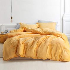 a bed with yellow comforters and pillows in a white room next to a lamp