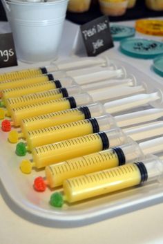 several plastic tubes with gummy bears in them sitting on a table next to cupcakes