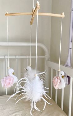 a white crib with pink flowers and feathers hanging from it