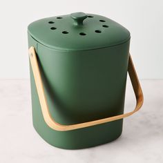 a green container with wooden handles on a table