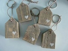 six wooden tags with white hearts are hanging on a string and tied to the wall