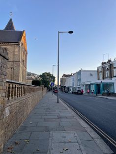 an empty city street lined with brick buildings and tall towers on either side of the road