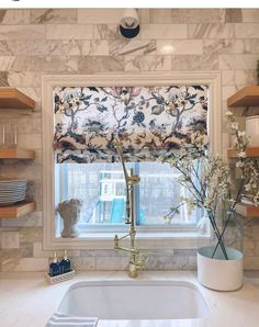 a kitchen sink under a window with roman blinds