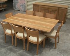 a wooden table with six chairs and a cabinet in the back ground, next to it