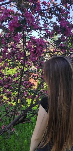 a woman sitting in front of a tree with purple flowers