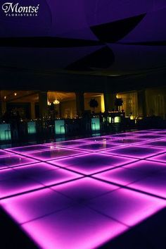 the dance floor is lit up with purple lights