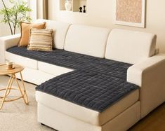 a living room with a white couch and brown pillows on the floor next to a window