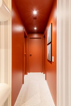 an empty hallway with red walls and white carpeted flooring is pictured in this image