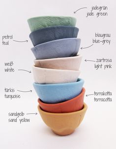 a stack of different colored bowls sitting on top of each other in front of a white background