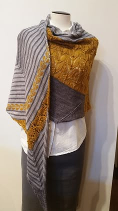 a mannequin wearing a yellow and gray shawl on top of a white wall