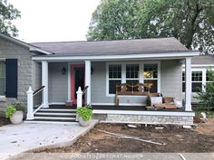 a small gray house with red door and steps leading up to the front porch area