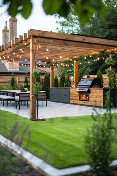 an outdoor kitchen and dining area is lit up at night with string lights strung across the pergolated roof