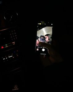 someone is holding up their cell phone to take a photo in the car at night