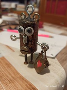 a small metal object with eyes and chains on it's head sitting on a table