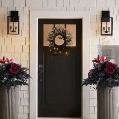 two metal planters with christmas wreaths on the front door