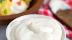 a bowl filled with whipped cream next to some other bowls full of desserts in the background