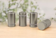 three metal cylinders sitting next to each other on a wooden table with flowers in the background