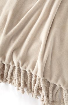 a white blanket with tassels on top of it