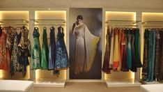 a woman is standing in front of an open closet with dresses hanging on the walls