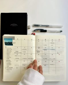 a person's hand is holding an open planner