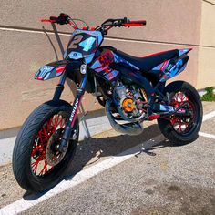 a blue and red dirt bike parked next to a building