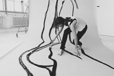 a woman is bending over on the floor with her hands and legs bent down as she looks at an art installation