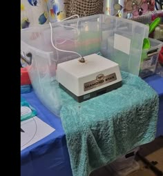 an electronic device sitting on top of a blue table covered in plastic storage bins