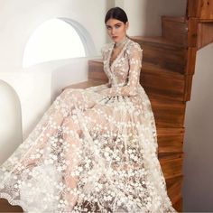 a woman is sitting on the stairs in a dress that has flowers all over it