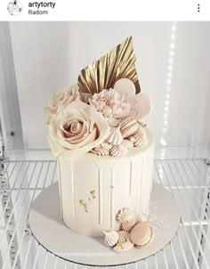 there is a white cake with gold decorations on the top and flowers on the bottom