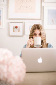 a woman drinking coffee while using her laptop