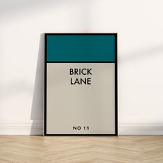 a framed poster with the words brick lane in black and white on a wood floor